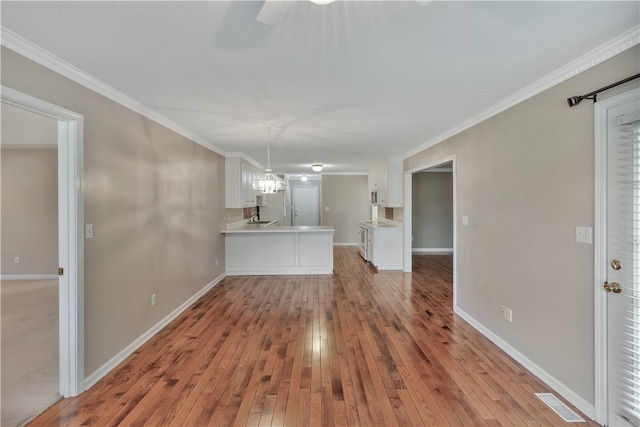 unfurnished living room with an inviting chandelier, crown molding, hardwood / wood-style floors, and sink