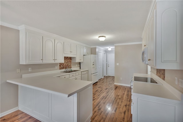 kitchen featuring light wood-type flooring, sink, white cabinetry, kitchen peninsula, and white appliances