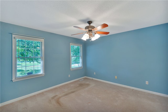 carpeted spare room featuring ceiling fan and a textured ceiling