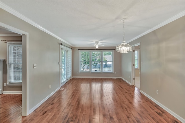 unfurnished dining area with ornamental molding, ceiling fan with notable chandelier, and hardwood / wood-style floors