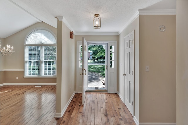 foyer entrance with light wood-type flooring, lofted ceiling with beams, ornamental molding, and a chandelier