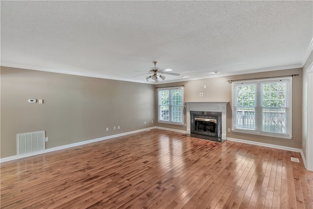 unfurnished living room with ceiling fan, ornamental molding, a high end fireplace, a textured ceiling, and light hardwood / wood-style floors