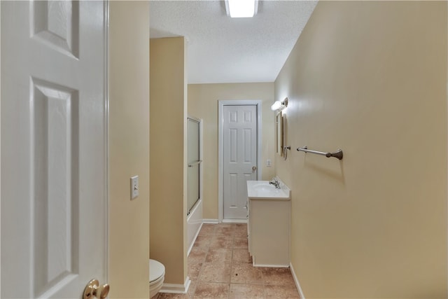 full bathroom with a textured ceiling, vanity, toilet, and bath / shower combo with glass door