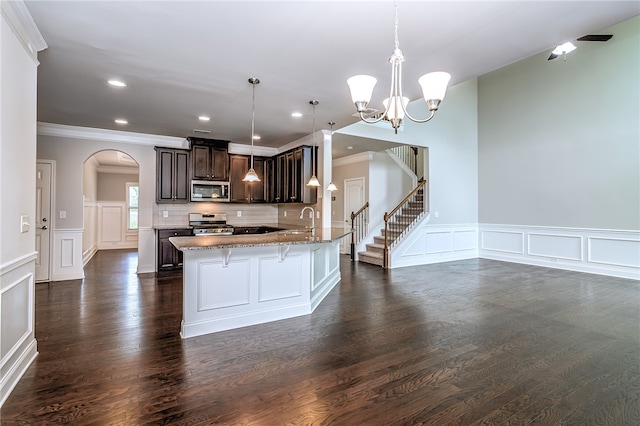 kitchen with dark brown cabinetry, decorative light fixtures, backsplash, dark wood-type flooring, and appliances with stainless steel finishes