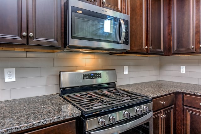 kitchen featuring dark stone counters, stainless steel appliances, and backsplash