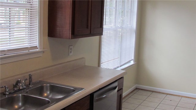 kitchen featuring dark brown cabinets, stainless steel dishwasher, light tile patterned flooring, and sink