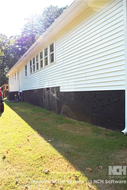 view of side of property with central AC and a yard