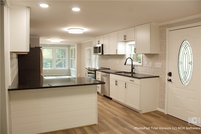 kitchen featuring white cabinetry, sink, stainless steel appliances, and light hardwood / wood-style floors