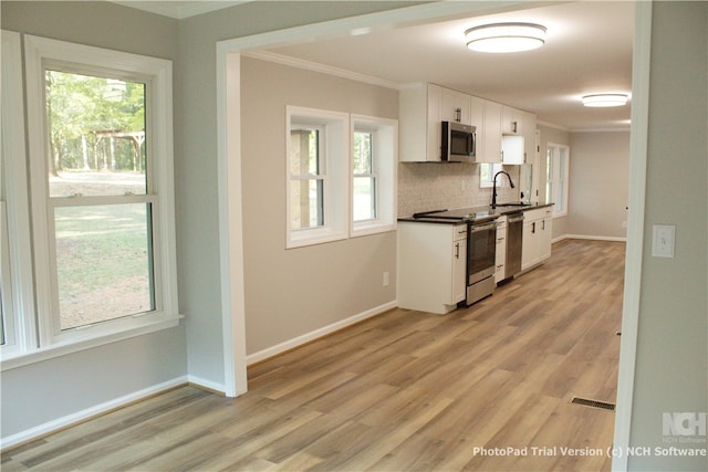 kitchen with light wood-type flooring, stainless steel appliances, white cabinetry, and sink