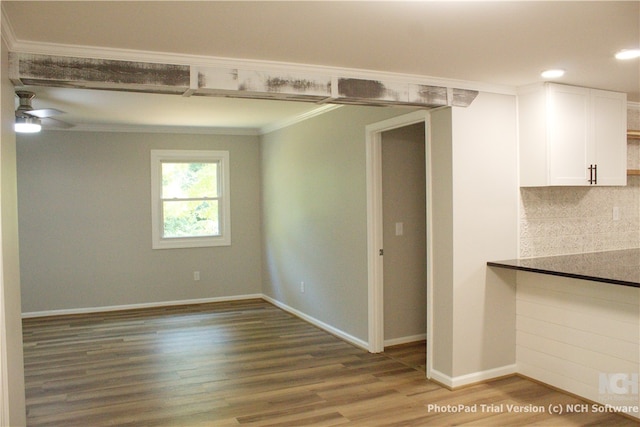 spare room featuring wood-type flooring, ceiling fan, and ornamental molding