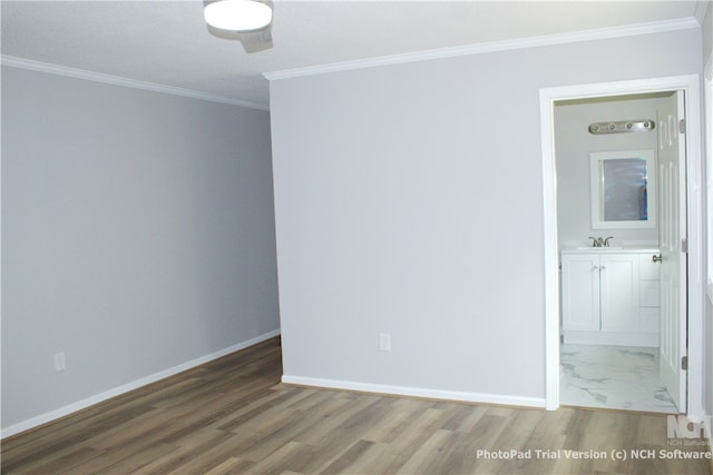 spare room with hardwood / wood-style flooring, sink, and crown molding