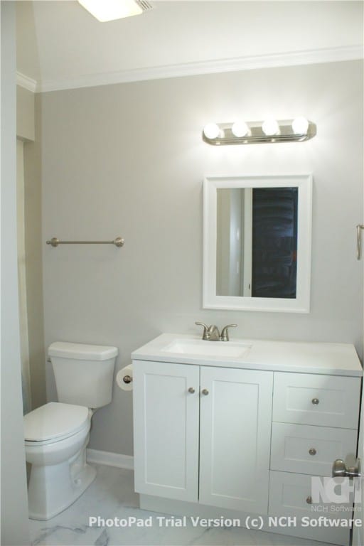 bathroom with toilet, vanity, and ornamental molding