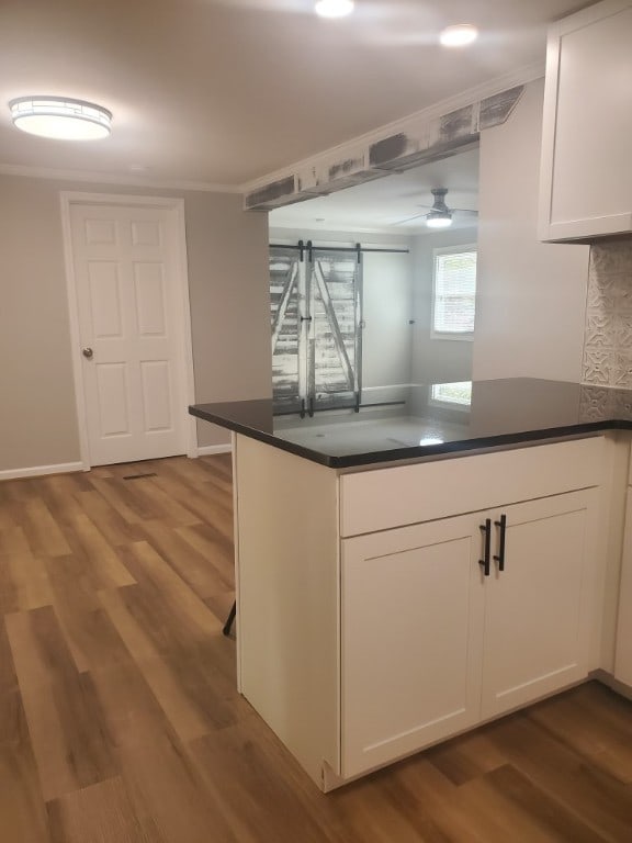 kitchen featuring kitchen peninsula, a barn door, light hardwood / wood-style flooring, and white cabinetry