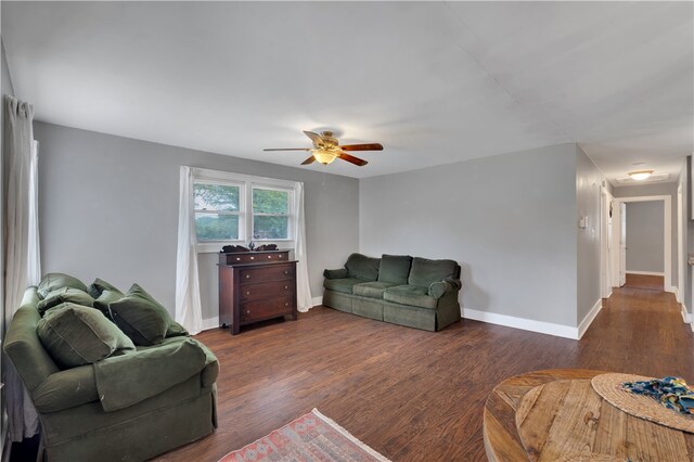 living room featuring ceiling fan and dark wood-type flooring