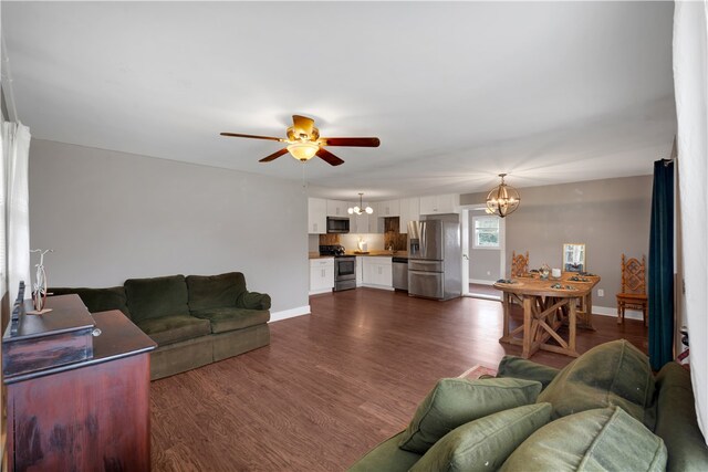 living room featuring ceiling fan with notable chandelier and dark hardwood / wood-style floors