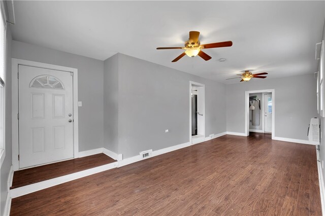 unfurnished living room featuring ceiling fan and dark wood-type flooring