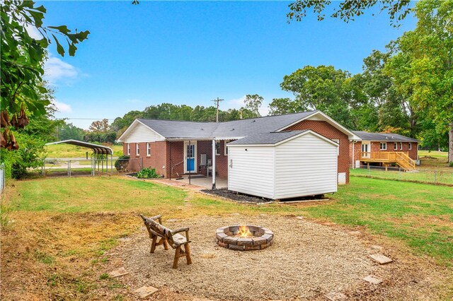 rear view of property with a storage shed, a wooden deck, an outdoor fire pit, and a yard