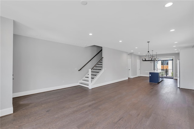 unfurnished living room with a notable chandelier, sink, and dark wood-type flooring