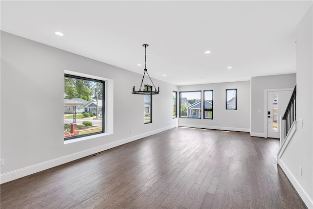 interior space with a healthy amount of sunlight, dark hardwood / wood-style flooring, and a notable chandelier