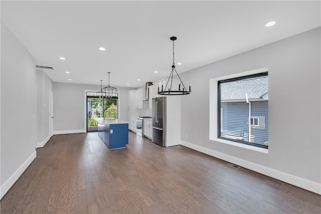 kitchen with white cabinets, pendant lighting, a kitchen island, stainless steel appliances, and dark hardwood / wood-style flooring