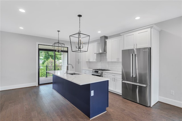 kitchen featuring sink, high end appliances, white cabinetry, wall chimney exhaust hood, and a center island with sink