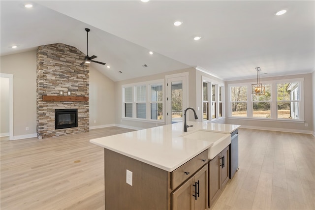 kitchen featuring dishwasher, an island with sink, lofted ceiling, light hardwood / wood-style flooring, and decorative light fixtures