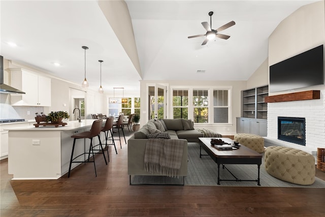 living room featuring a brick fireplace, vaulted ceiling, ceiling fan, and dark hardwood / wood-style flooring