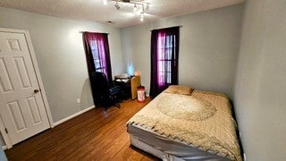 bedroom with a textured ceiling, dark hardwood / wood-style flooring, and rail lighting