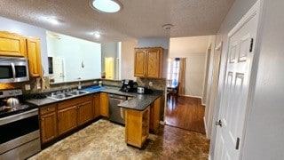 kitchen with sink, appliances with stainless steel finishes, a textured ceiling, and hardwood / wood-style floors