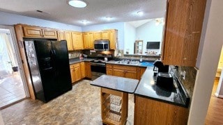 kitchen featuring black refrigerator, range, backsplash, and kitchen peninsula