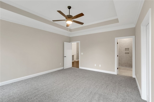 unfurnished bedroom with ornamental molding, carpet floors, connected bathroom, a raised ceiling, and ceiling fan