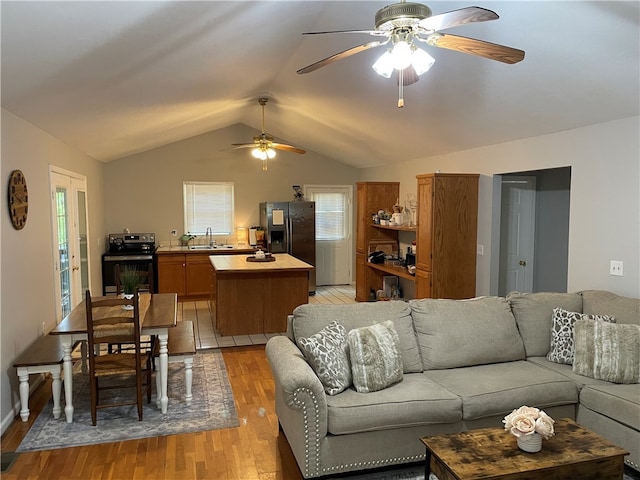 living room featuring light wood-type flooring, lofted ceiling, sink, and ceiling fan