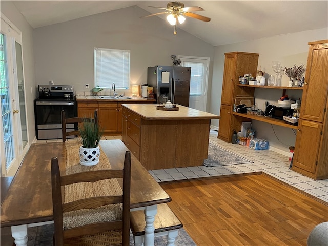 kitchen with tile counters, light hardwood / wood-style floors, vaulted ceiling, ceiling fan, and appliances with stainless steel finishes