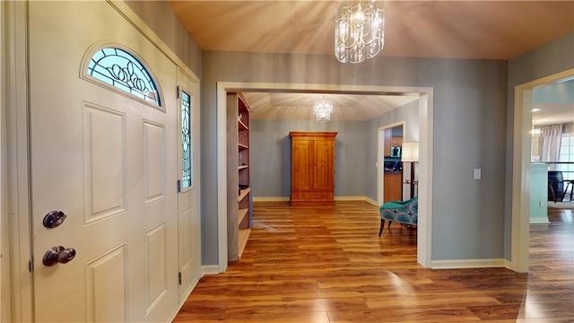 foyer entrance with a chandelier, wood finished floors, and baseboards