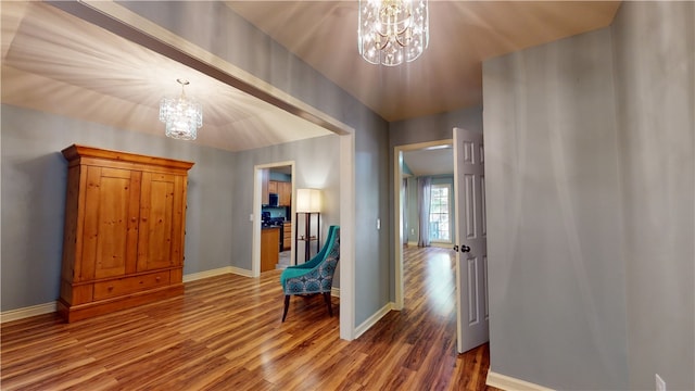 hallway featuring wood-type flooring and an inviting chandelier