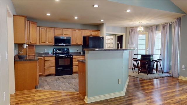 kitchen featuring black appliances, decorative light fixtures, a chandelier, light hardwood / wood-style floors, and a kitchen island