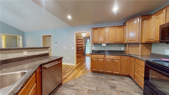 kitchen featuring light wood-type flooring, dark stone counters, stainless steel appliances, vaulted ceiling, and sink