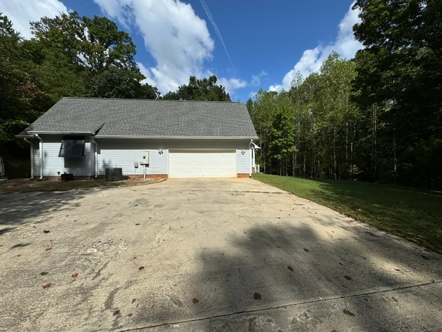 view of side of property with central AC, a garage, and a lawn