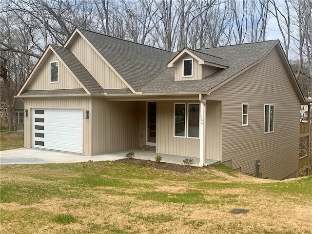 view of front of property with a front yard, roof with shingles, driveway, and an attached garage