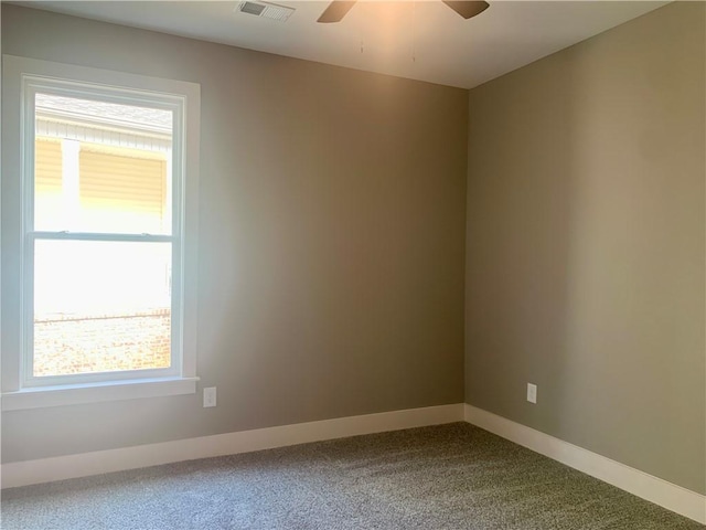 unfurnished room with baseboards, visible vents, dark carpet, and a ceiling fan