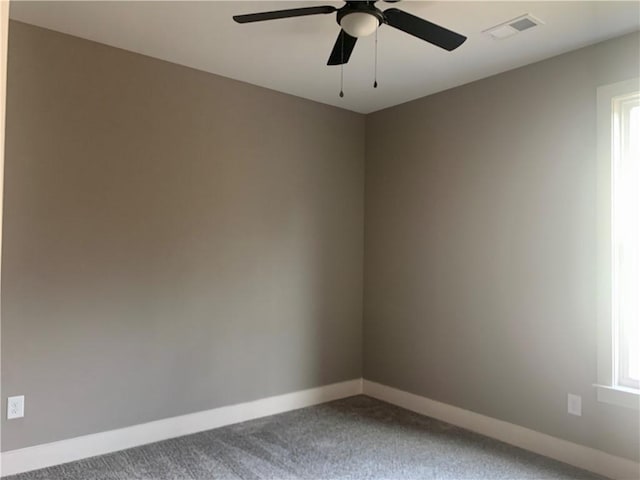 empty room featuring ceiling fan, carpet flooring, visible vents, and baseboards