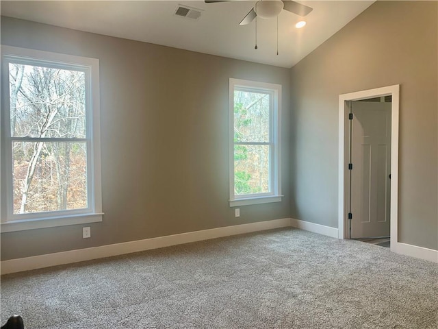 carpeted spare room featuring lofted ceiling, visible vents, ceiling fan, and baseboards