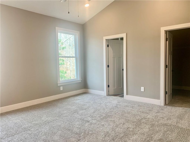 unfurnished bedroom with carpet floors, a spacious closet, baseboards, and lofted ceiling