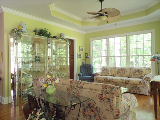 living room featuring a tray ceiling, crown molding, hardwood / wood-style floors, and ceiling fan