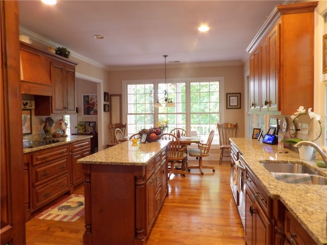 kitchen with pendant lighting, light stone countertops, a center island, and light wood-type flooring