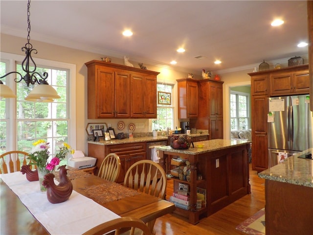 kitchen with stainless steel fridge, a kitchen island, a wealth of natural light, and hanging light fixtures