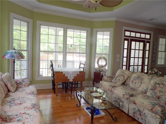 living room with light wood-type flooring, crown molding, and a wealth of natural light