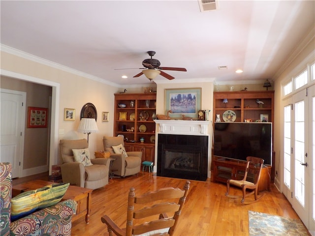 living room with plenty of natural light, light hardwood / wood-style floors, ornamental molding, and ceiling fan