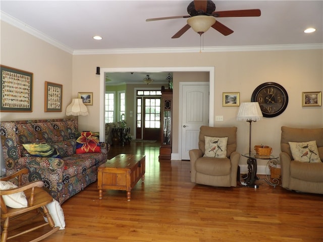 living room with wood-type flooring, ornamental molding, and ceiling fan