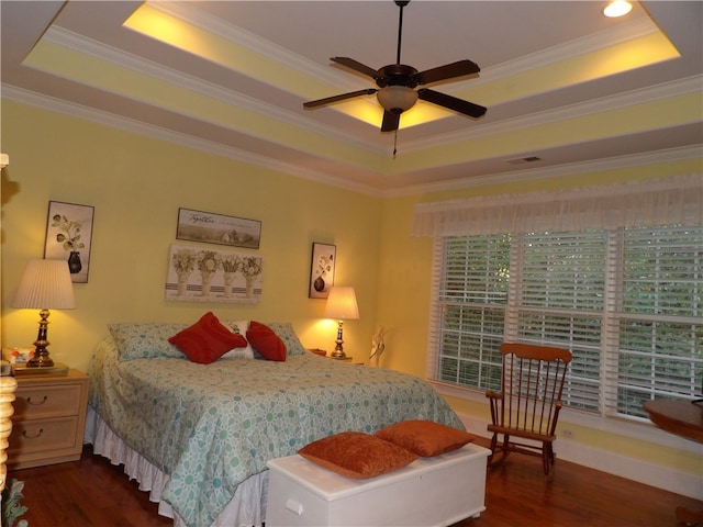 bedroom featuring ornamental molding, ceiling fan, dark wood-type flooring, and a raised ceiling